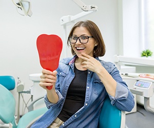Woman smiling in dental chair looking at mirror
