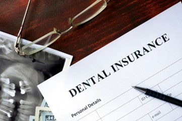 Dental insurance paperwork lying on desk with X-rays