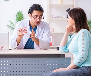 A dentist goes over the process of receiving dental implants with a female patient