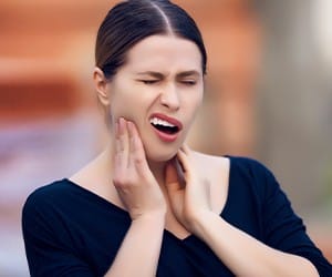 Woman with lost filling holding jaw in pain