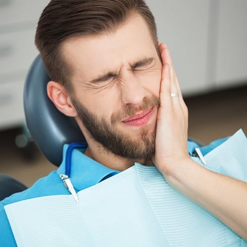 Man in need of emergency dentistry holding jaw