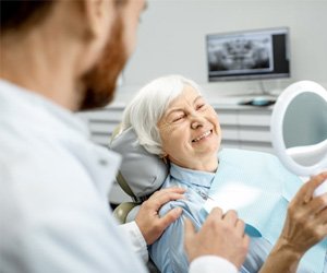 a patient checking her dental implants with a mirror