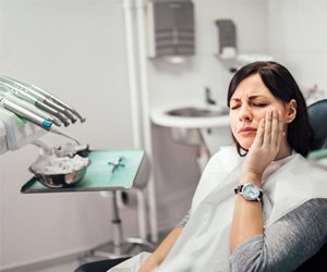 : a patient touching her cheek due to failed dental implant