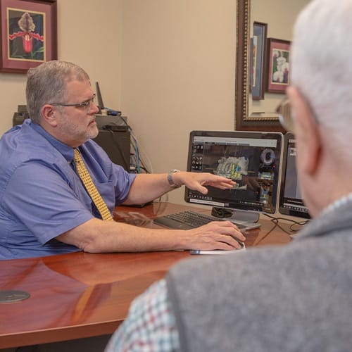 Dentist showing patient gum grafting treatment plan on computer screen