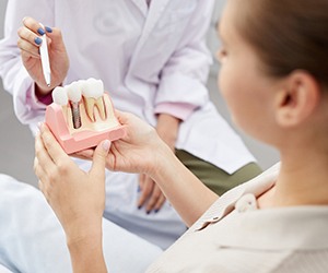 A dentist explaining long-term dental implant benefits using a model