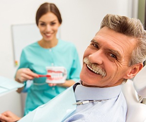 Older man with mustache smiling in dental chair