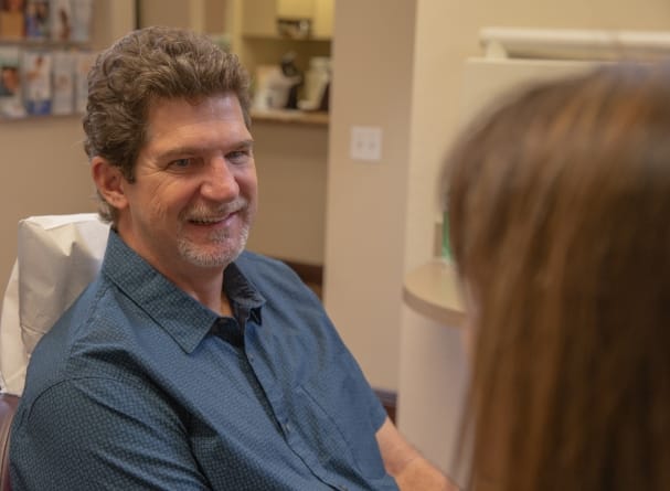 Dental patient smiling after replacing teeth with dental implants