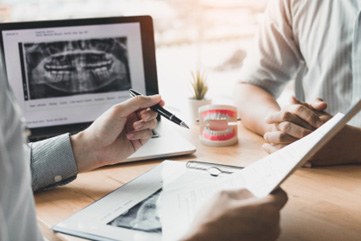 Dentist reviewing paperwork and dental X-rays with patient