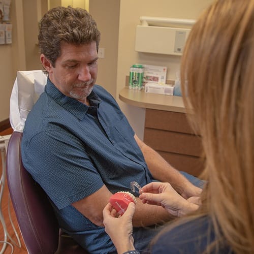 Dental team member showing dental patient how to place Invisalign treatment