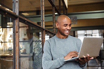 Man smiling while working on laptop in office