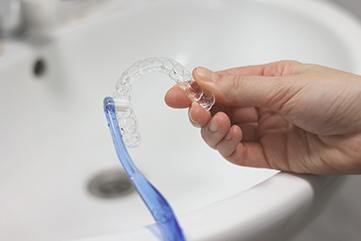 Patient cleaning clear aligner with toothbrush