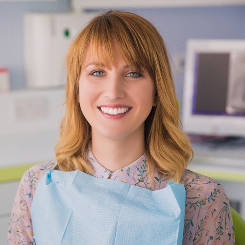 Red-haired woman sitting in dental chair and smiling