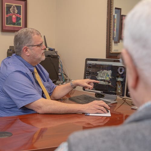 Dentist and patient looking at ridge augmentation treatment plan on computer screen