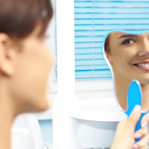 Patient looking at their smile in the mirror and appearing pleased