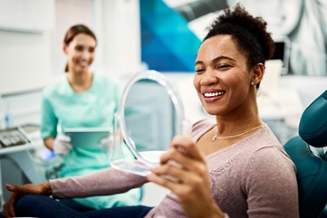 Woman smiling at reflection in dentist's mirror