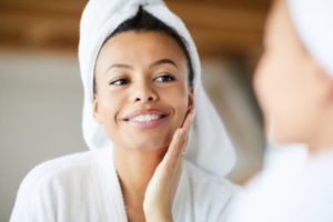 Woman smiling in mirror after seeing dentist in Fort Meyers