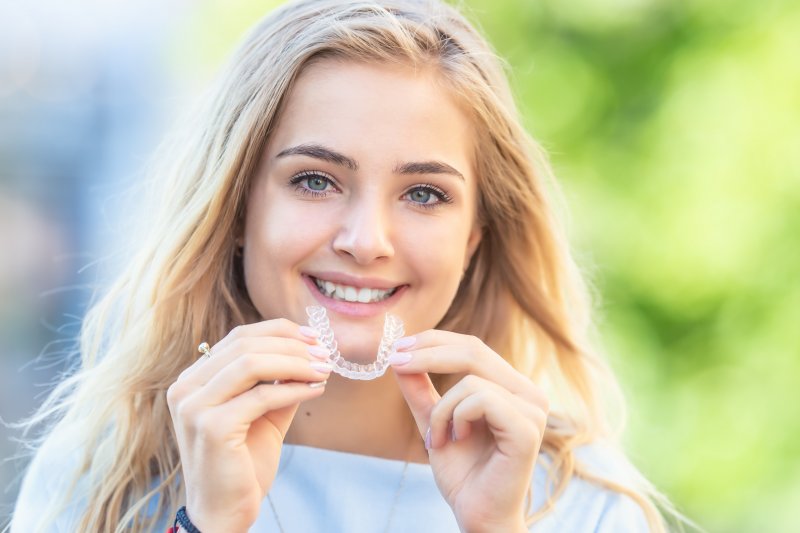 Woman with dental crowns about to wear Invisalign