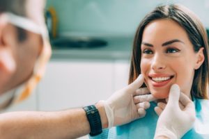 cosmetic dentist examining patient’s teeth