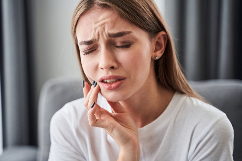 a young woman holds her mouth in pain because of a toothache in Fort Myers