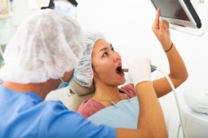 Patient pointing at monitor while intraoral camera is in her mouth