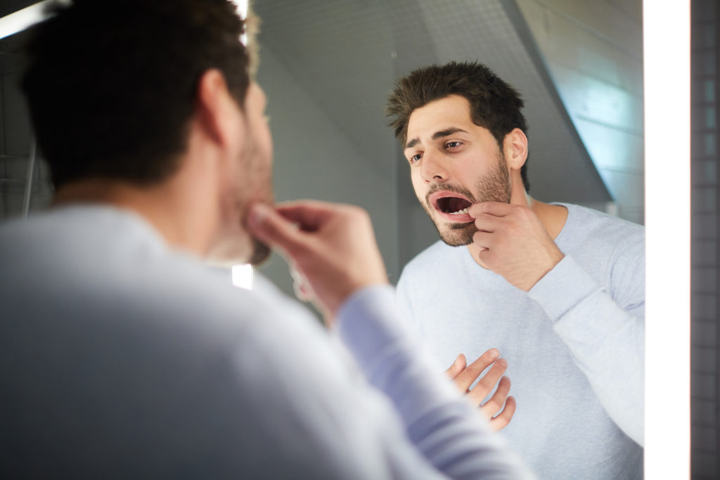 Man looking in the mirror at his dental implants